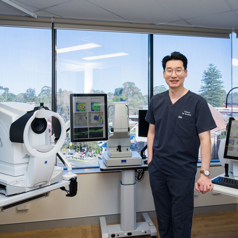 Dr John Chang stands with the advanced imaging equipment used to assess eye patients